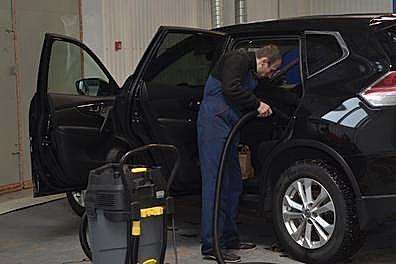 Мастер делает чистит внутренности салона машины с помощью спец.химии