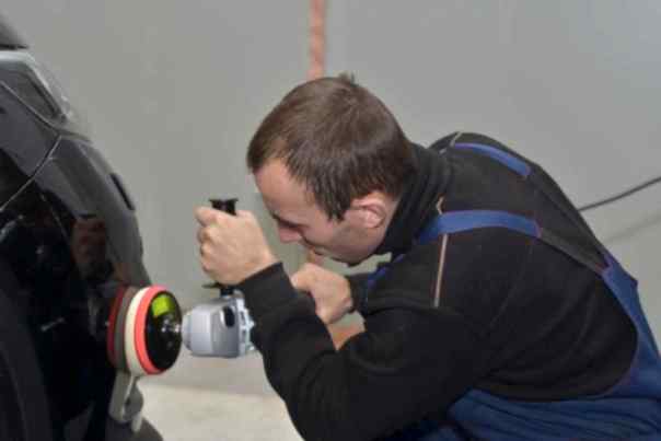 автомеханик полирует правый световой прибор