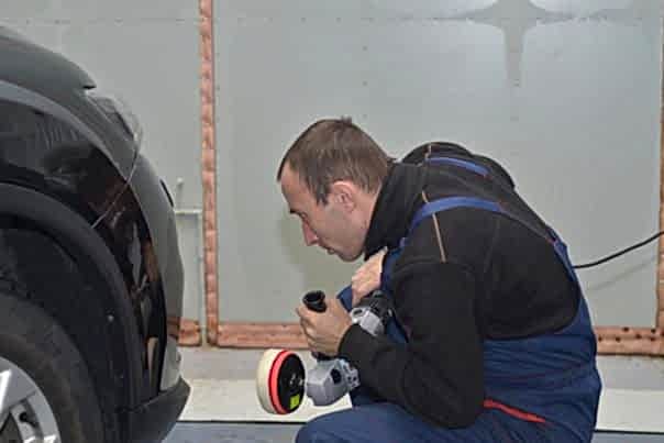 автомеханик полирует левую фару